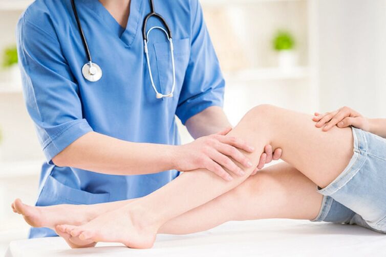 The doctor examines the leg with varicose veins